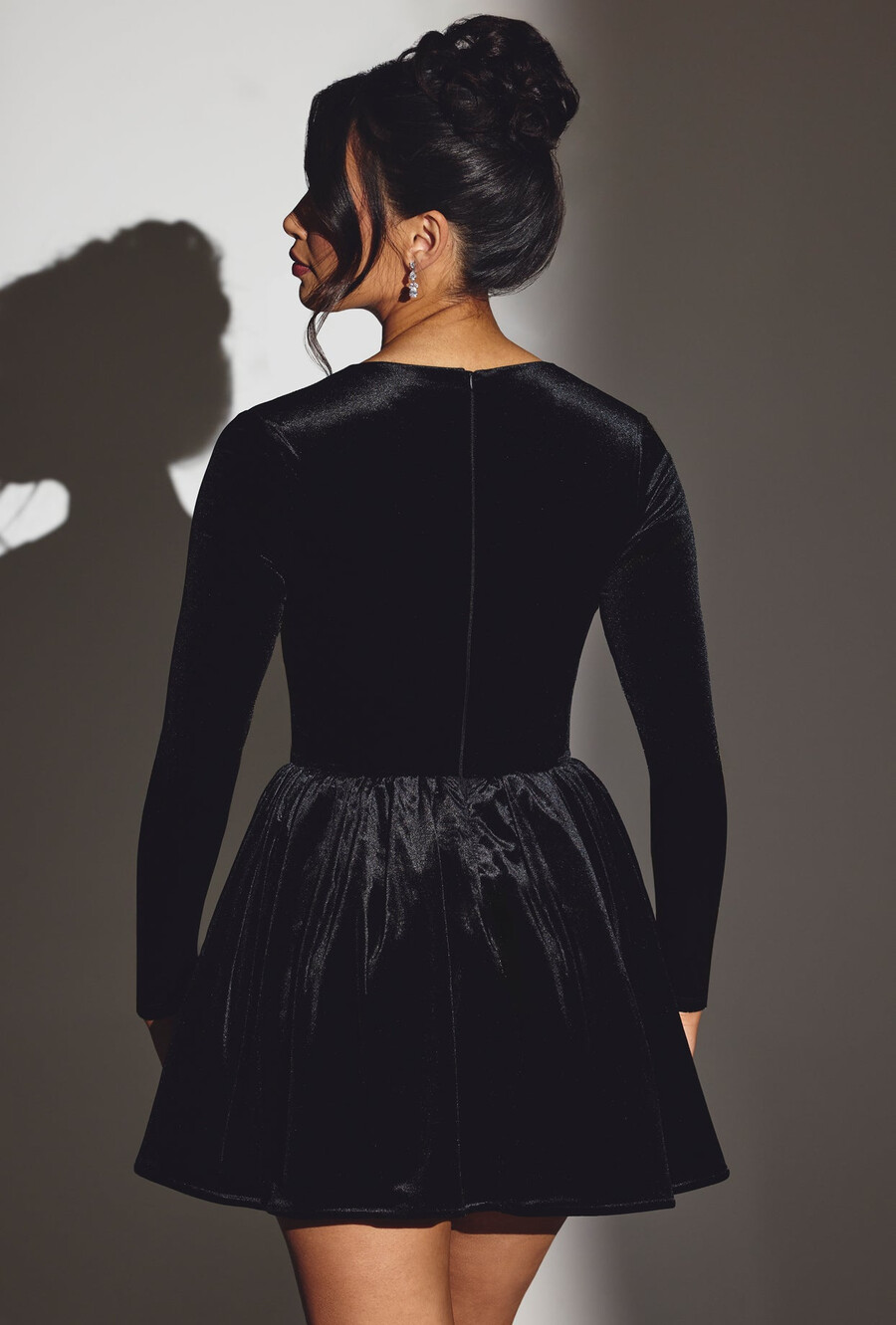 vestido curto de veludo preto com espartilho e mangas compridas.