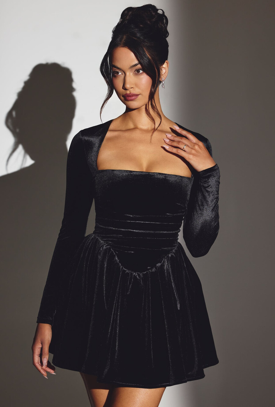 vestido curto de veludo preto com espartilho e mangas compridas.