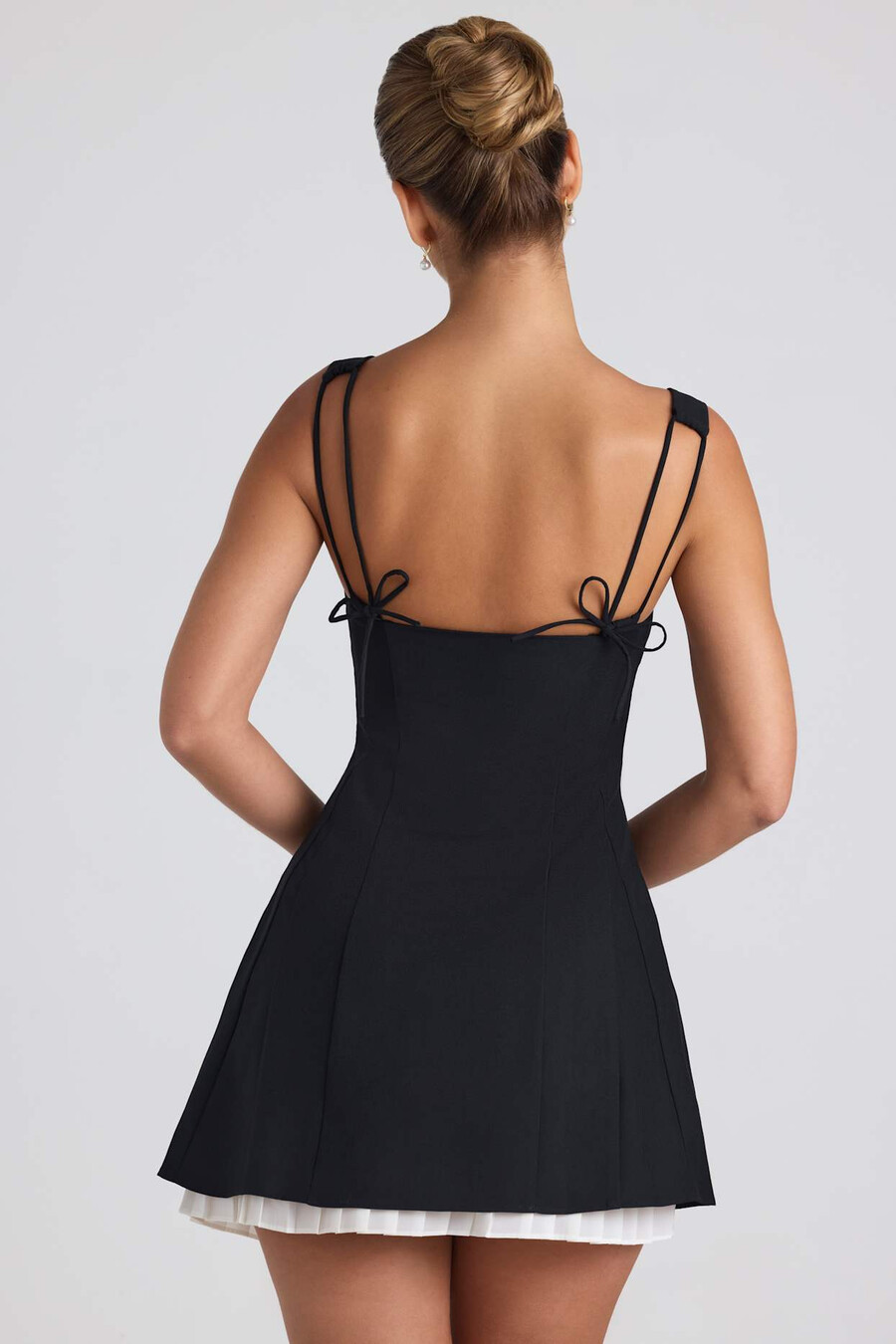 vestido curto evasê plissado com detalhe de laço na cor preta.