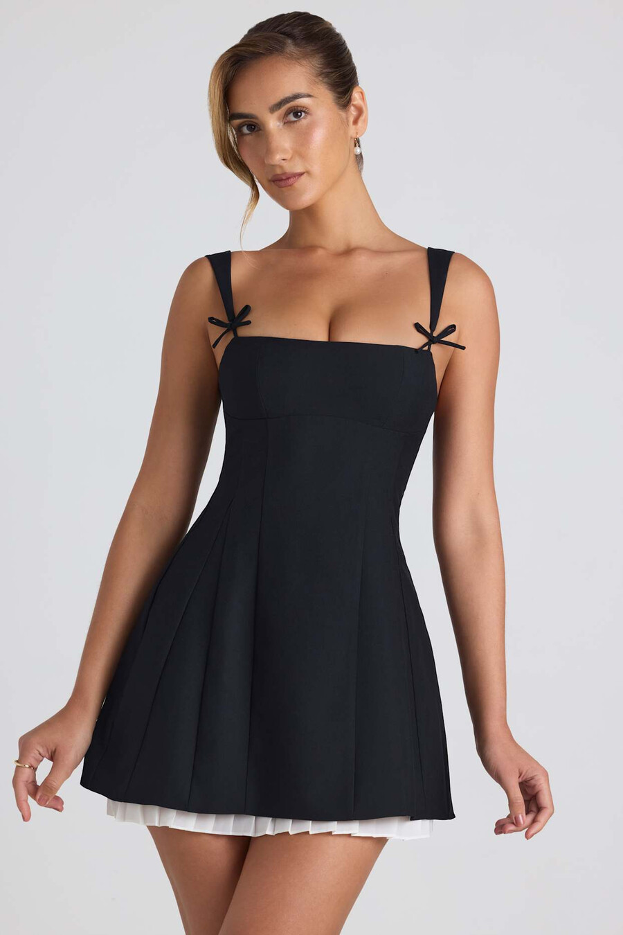 vestido curto evasê plissado com detalhe de laço na cor preta.