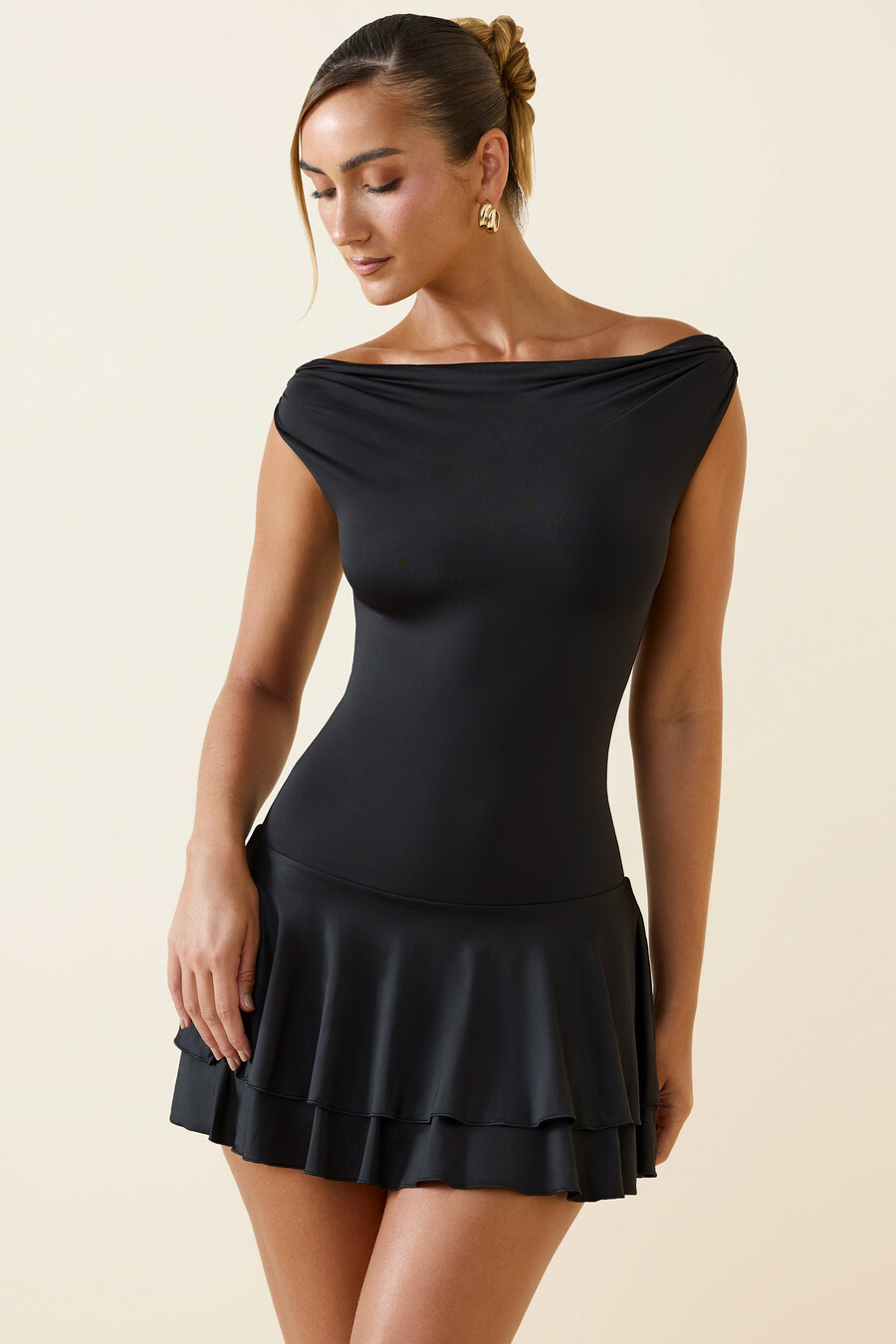 vestido curto preto com babados e ombros à mostra.