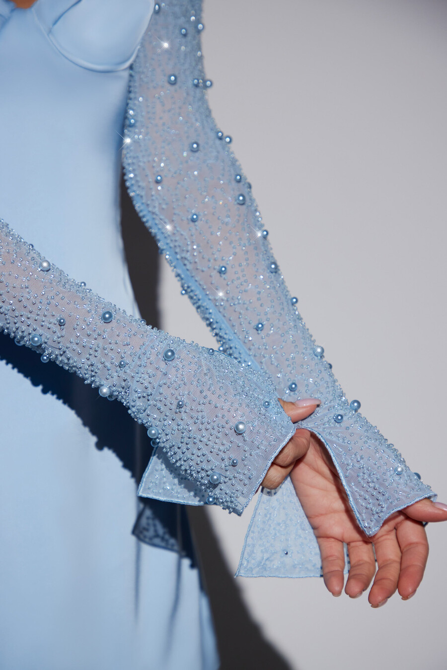 vestido curto evasê azul com mangas compridas e detalhes brilhantes.