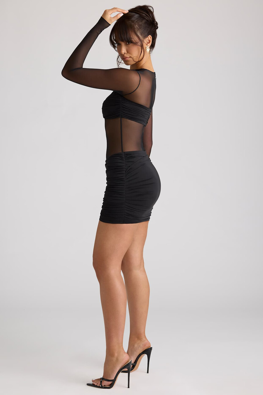 vestido curto preto com painéis transparentes e mangas compridas.