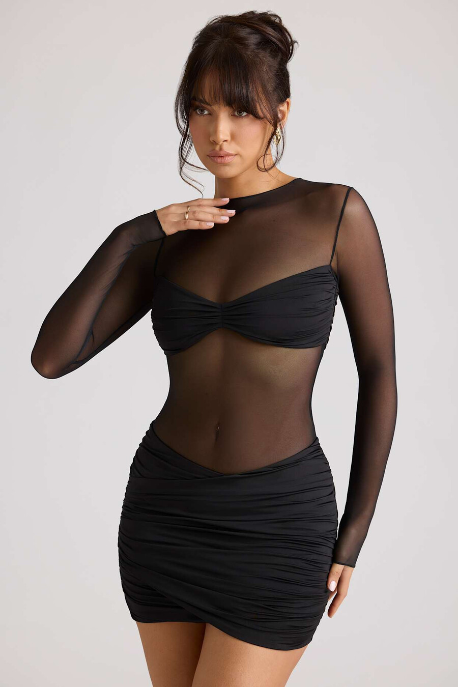 vestido curto preto com painéis transparentes e mangas compridas.