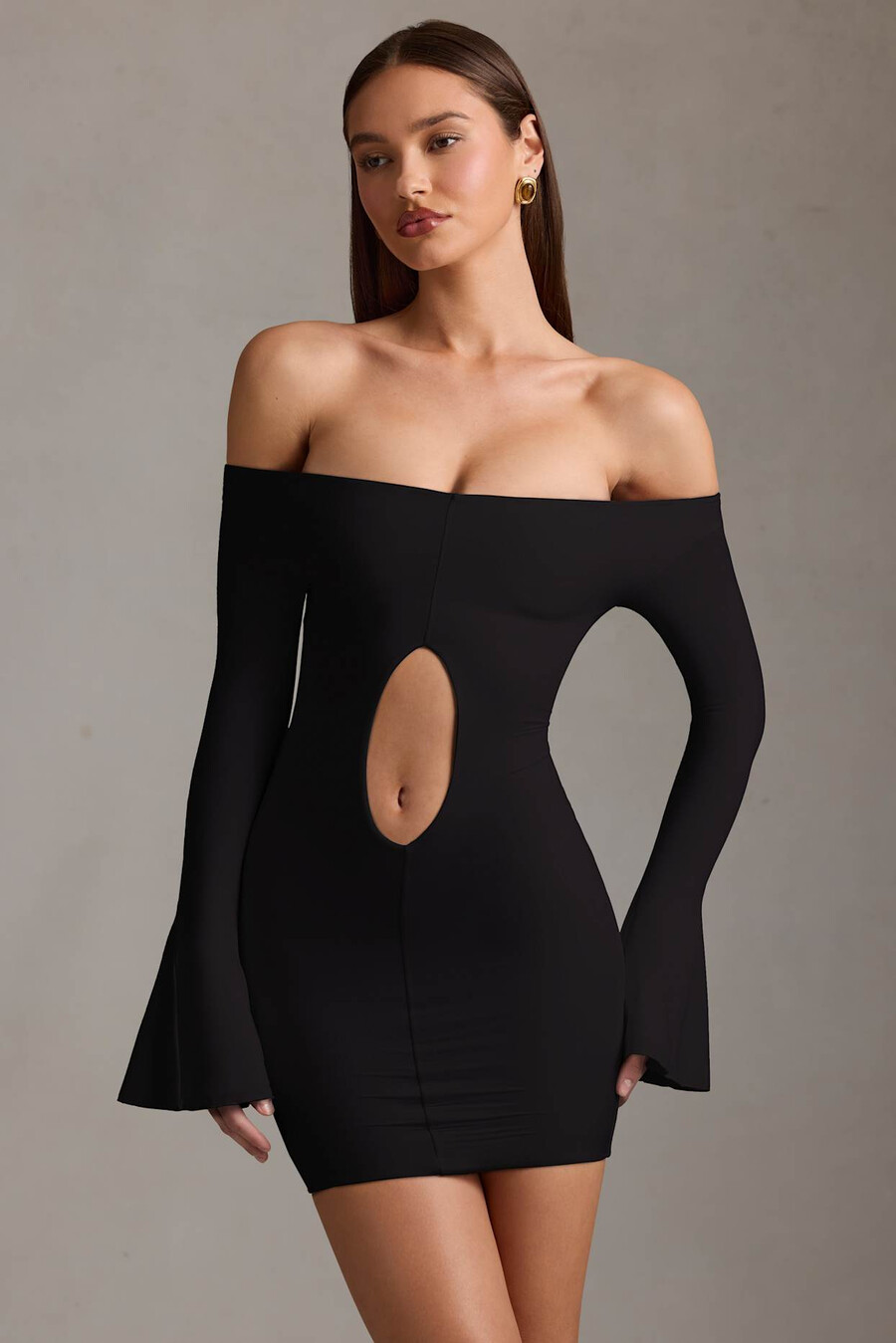 vestido curto preto com recortes e ombros à mostra.