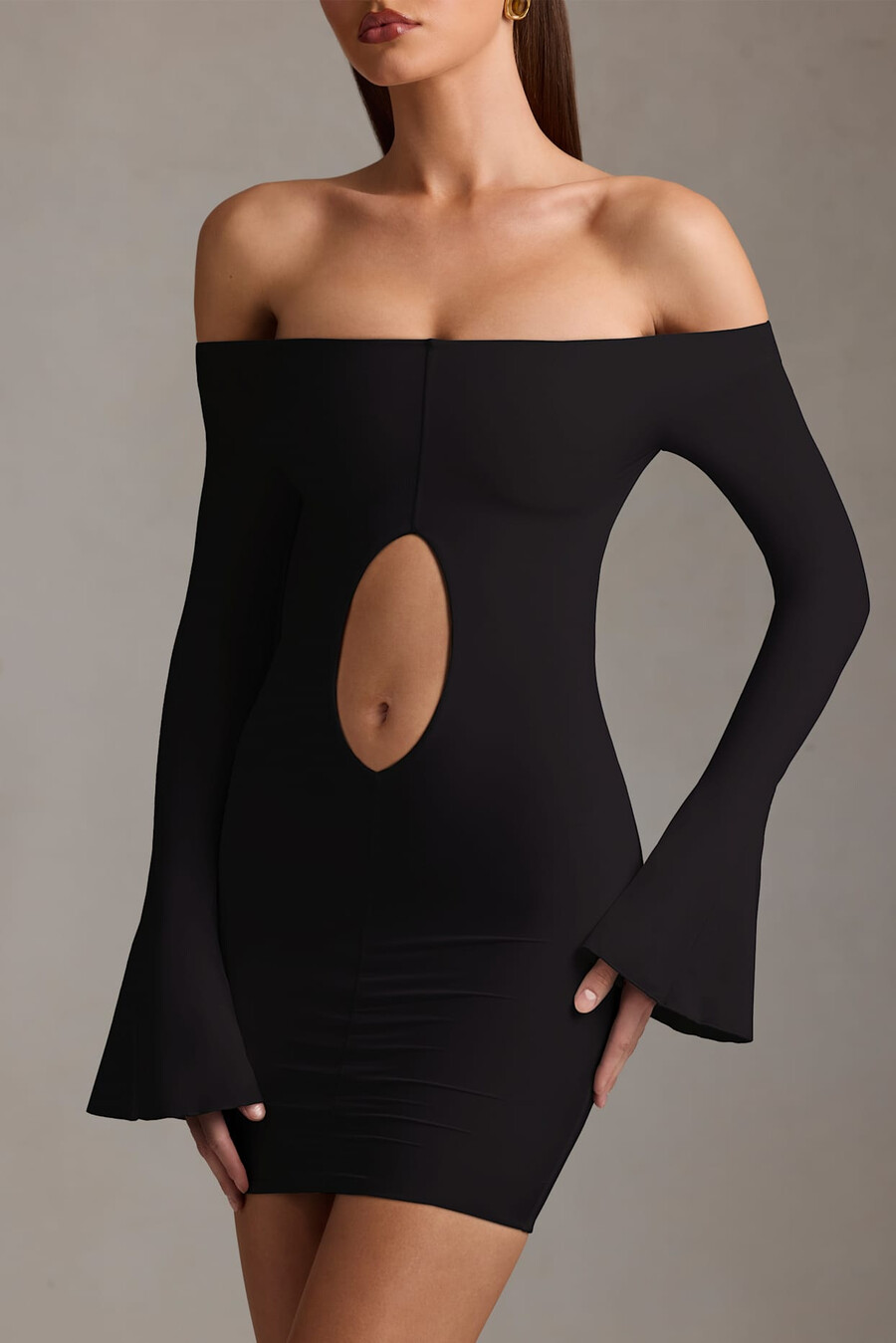 vestido curto preto com recortes e ombros à mostra.