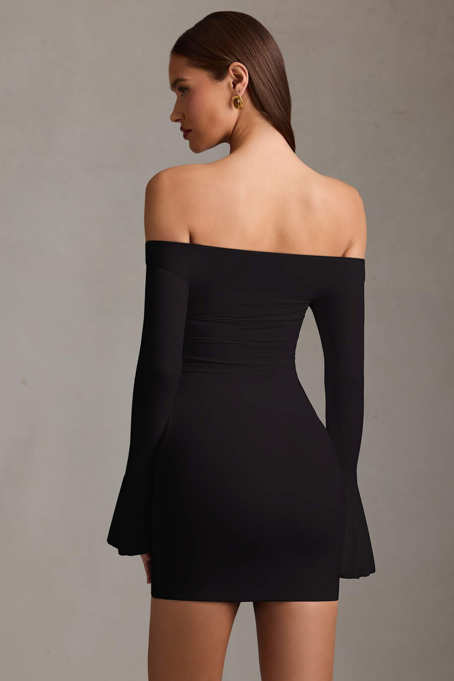 vestido curto preto com recortes e ombros à mostra.