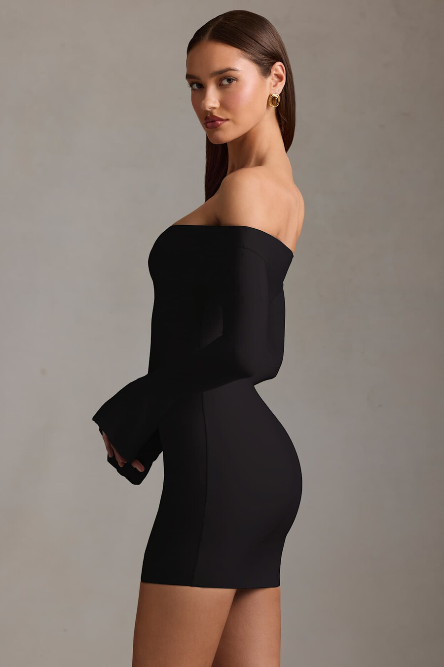 vestido curto preto com recortes e ombros à mostra.