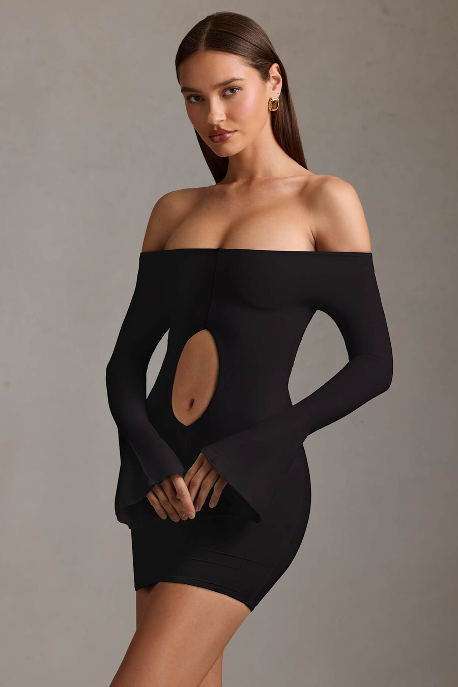 vestido curto preto com recortes e ombros à mostra.