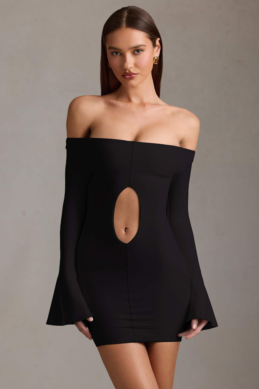 vestido curto preto com recortes e ombros à mostra.