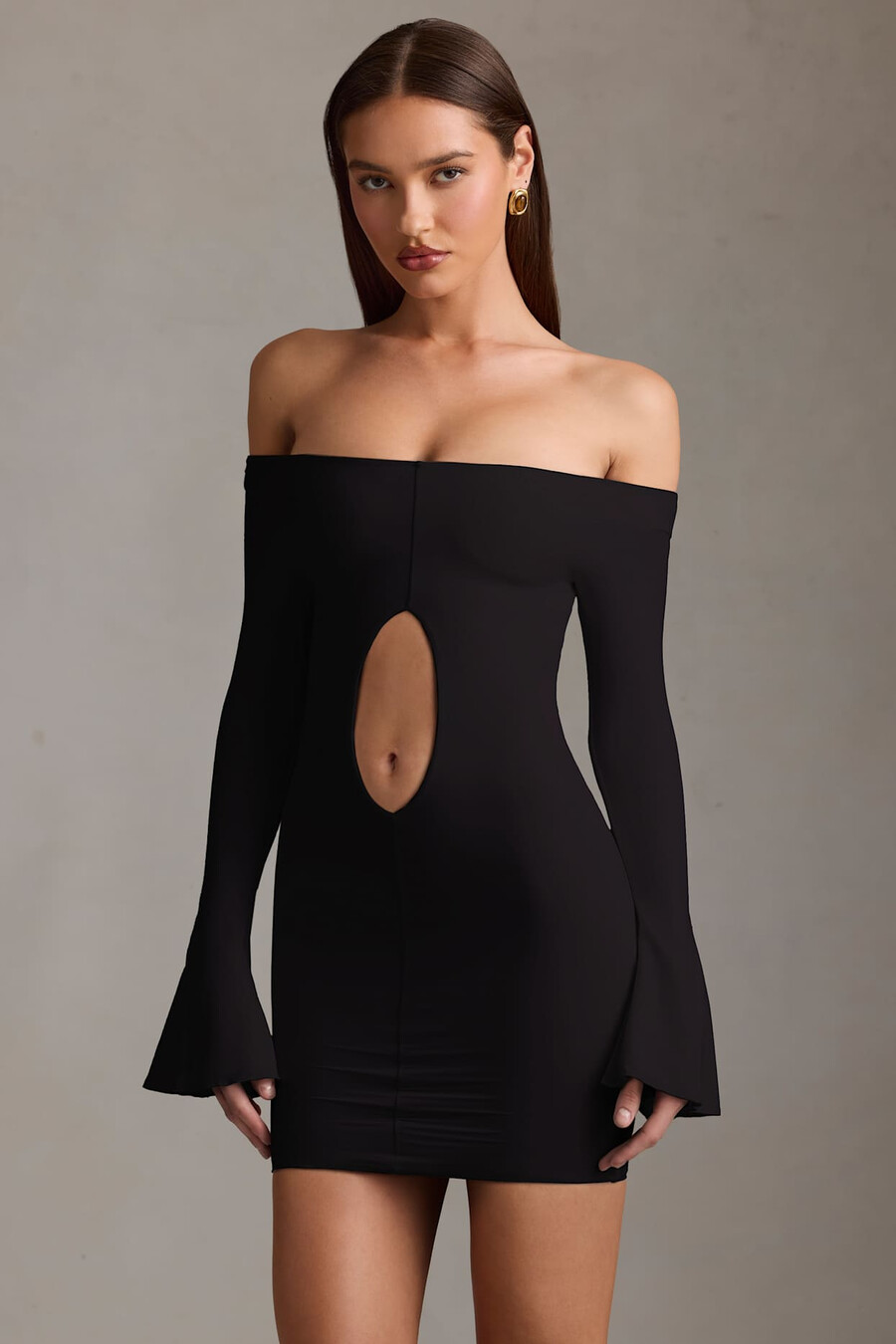 vestido curto preto com recortes e ombros à mostra.