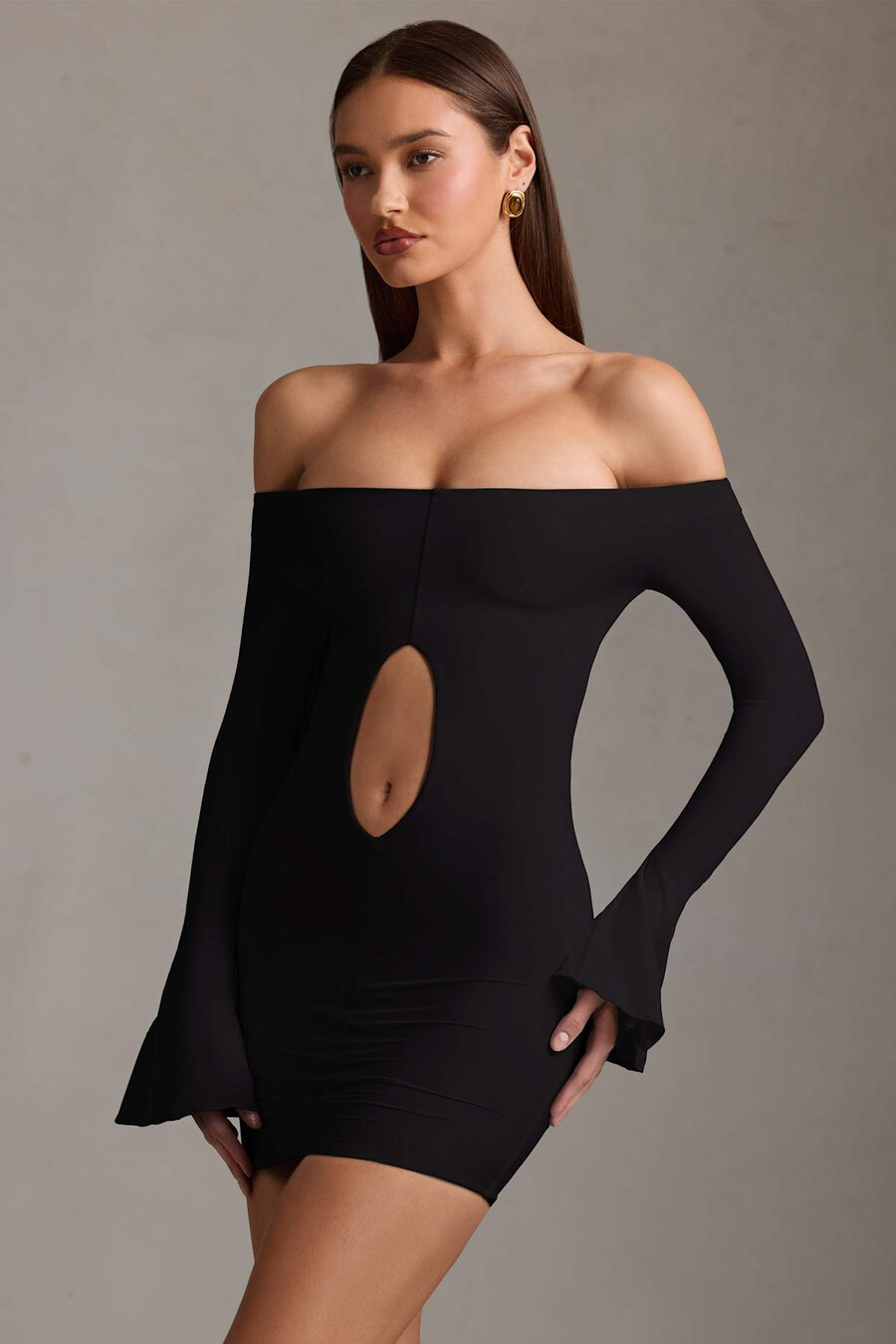 vestido curto preto com recortes e ombros à mostra.