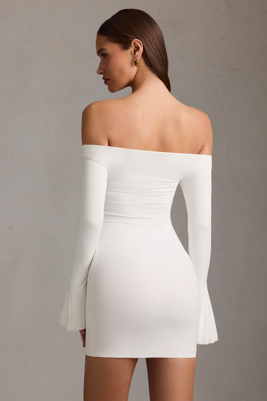 vestido curto branco com recortes e ombros à mostra.