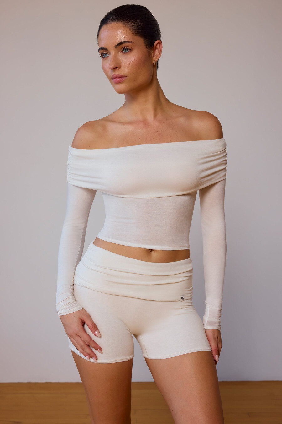 blusa transparente de manga comprida com ombros à mostra em tom branco suave.