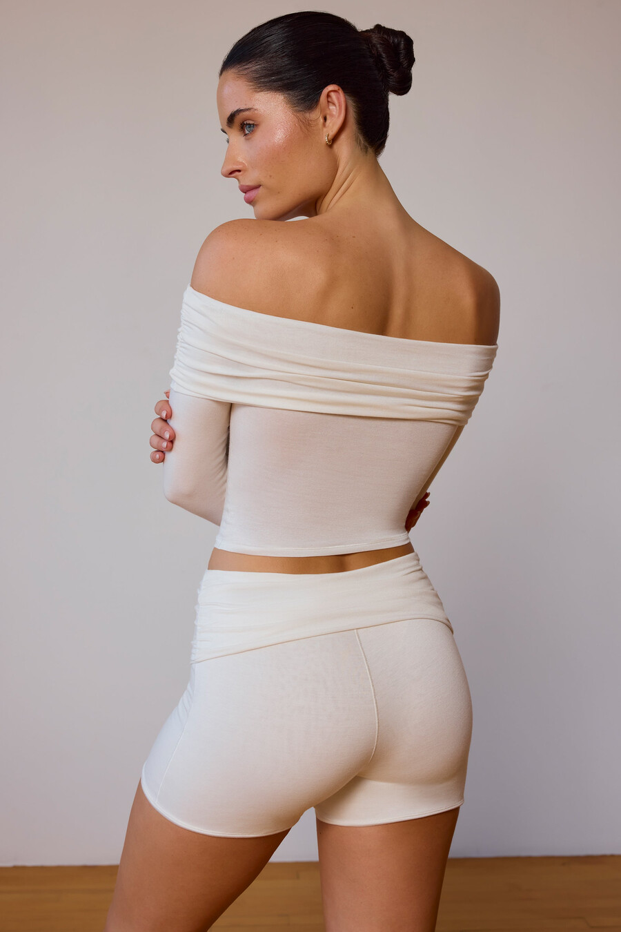 blusa transparente de manga comprida com ombros à mostra em tom branco suave.