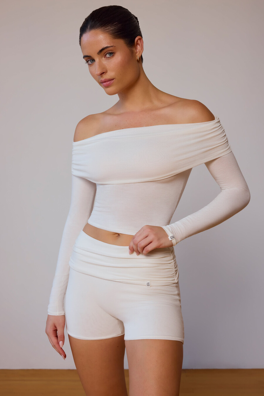 blusa transparente de manga comprida com ombros à mostra em tom branco suave.