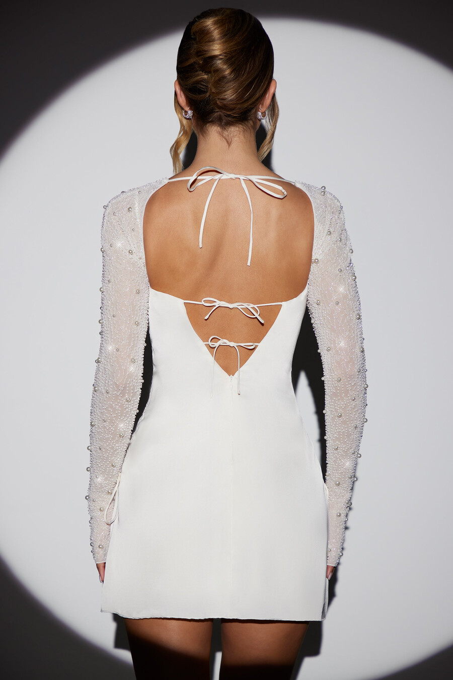 vestido curto evasê de manga comprida com detalhes brilhantes na cor branca.