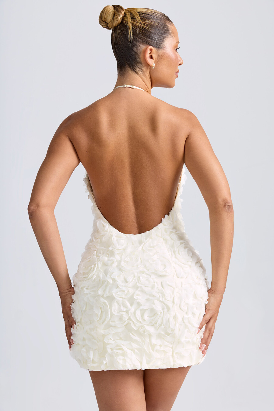 vestido curto evasê com decote halter e apliques florais na cor branca.